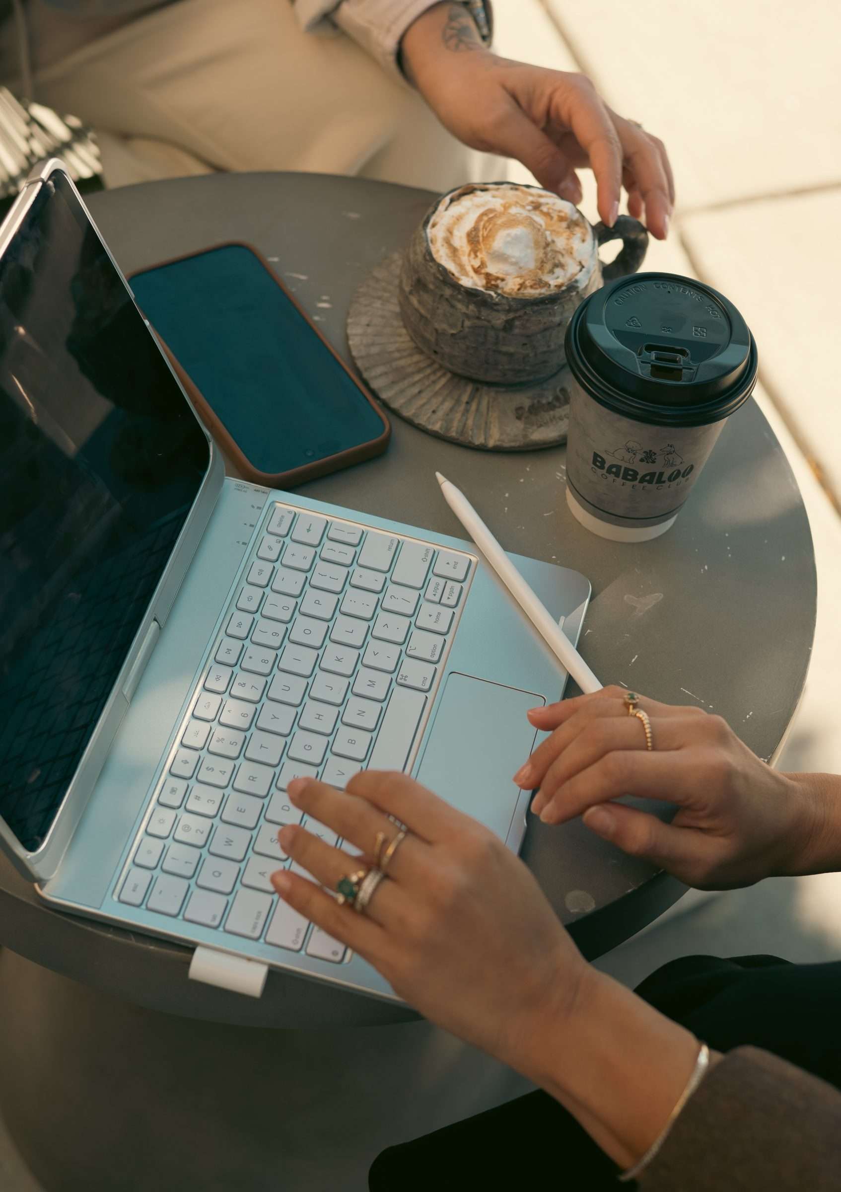 Working on a laptop with a Babaloo latte and a to-go cup
