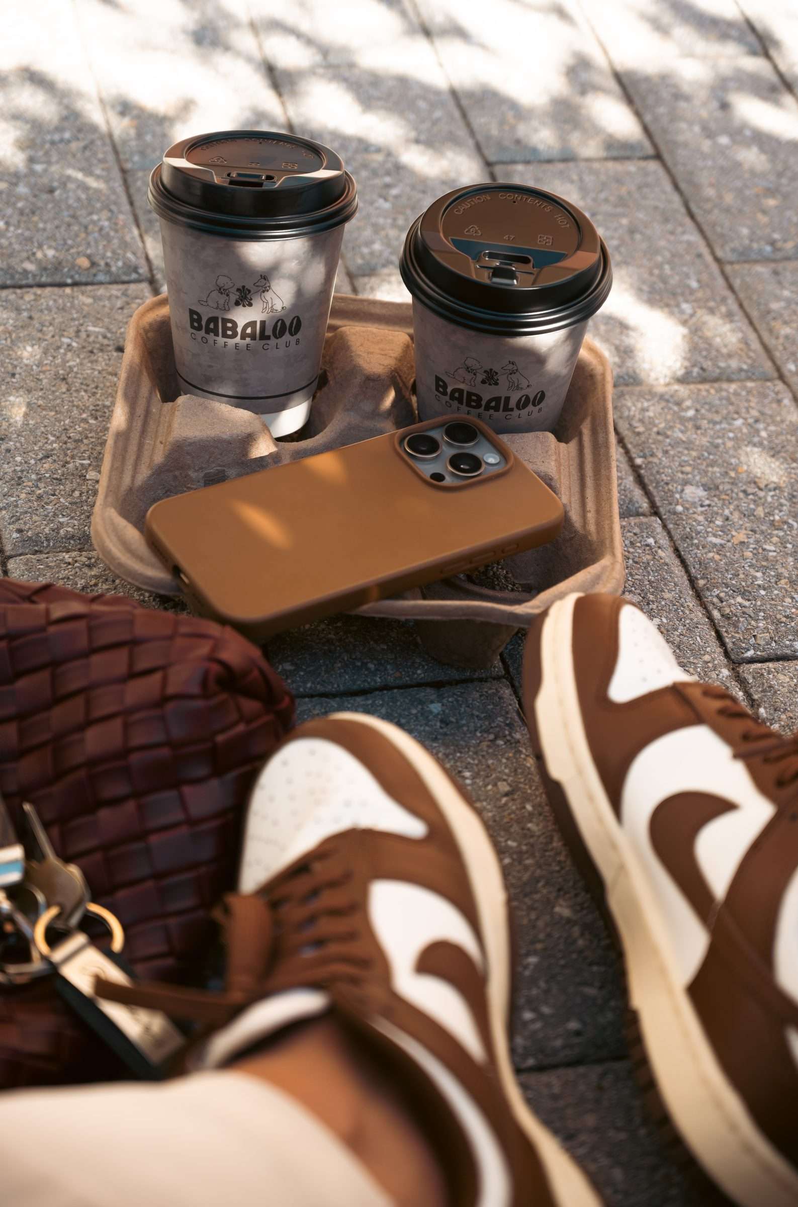 Two Babaloo to-go cups in a tray on a sunny pavement