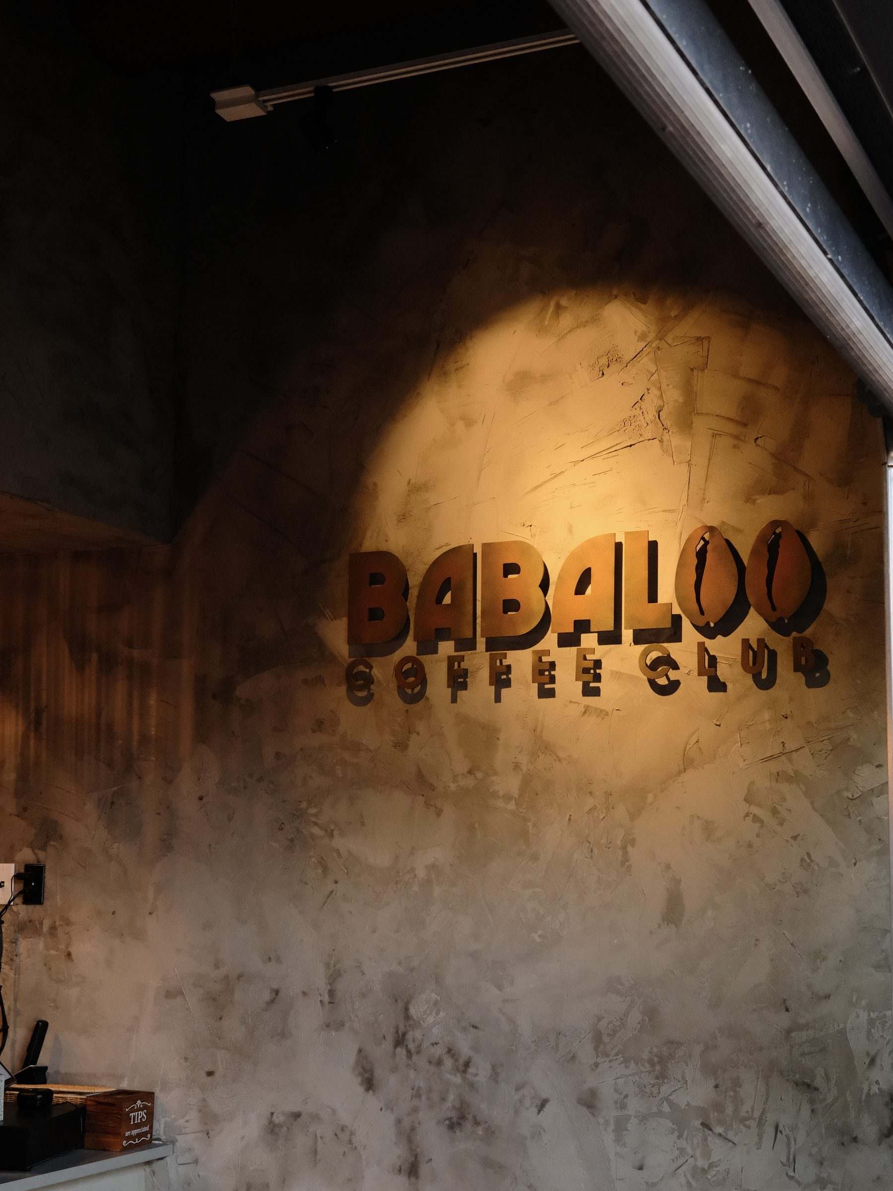 The Babaloo Coffee Club sign lit on a textured wall
