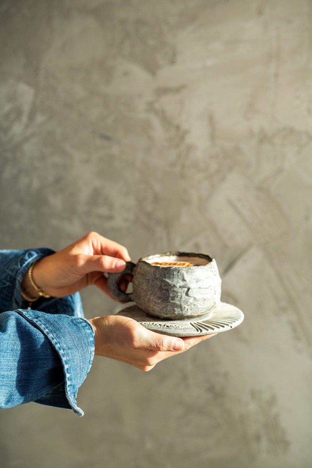 Cortado in a stoneware cup held by a guest