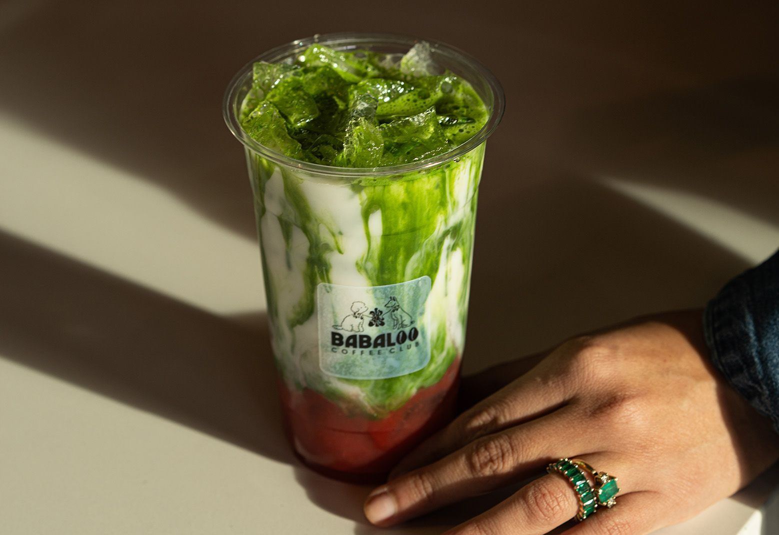 Layered green and red smoothie held in the sun