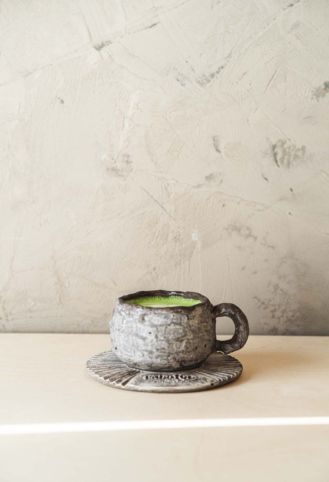 Stoneware cup of matcha on a sunlit table